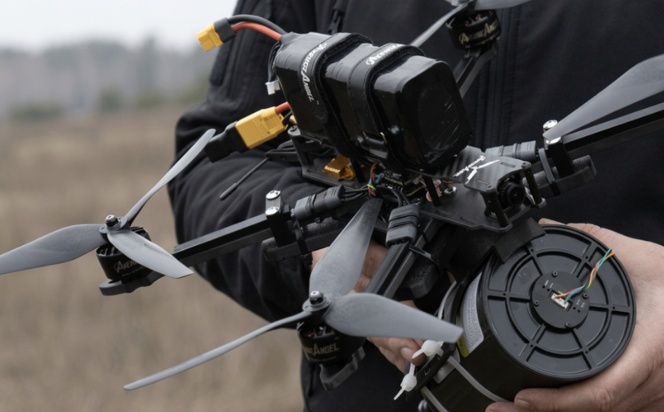 Operator holding a black SevHas Systems FPV quadcopter fitted with specialist equipment